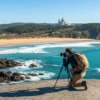 Solo pilgrim photographing Praia de Afife from a clifftop with Santa Luzia basilica in the background, one of the best photo spots on the Portuguese Coastal Camino.
