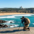 Solo pilgrim photographing Praia de Afife from a clifftop with Santa Luzia basilica in the background, one of the best photo spots on the Portuguese Coastal Camino.