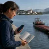 A pilgrim reviewing route notes near the Caminha riverside before crossing into Spain on the Portuguese Coastal Camino.